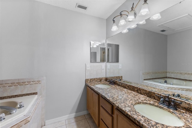 bathroom featuring tile patterned flooring, vanity, a textured ceiling, and tiled bath