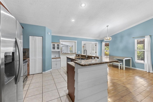 kitchen featuring stainless steel refrigerator with ice dispenser, stove, dark stone counters, sink, and decorative light fixtures