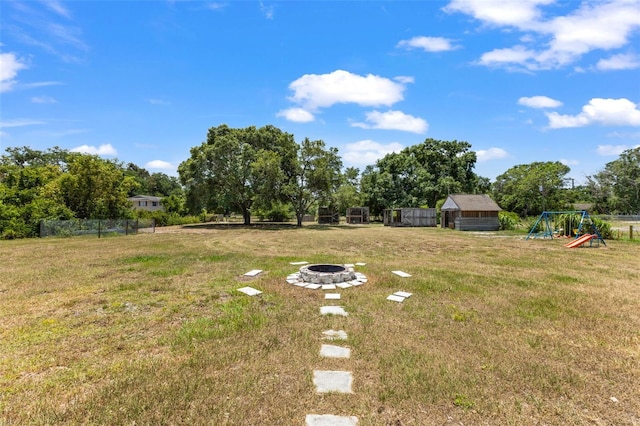 view of yard with a fire pit, an outdoor structure, and a playground