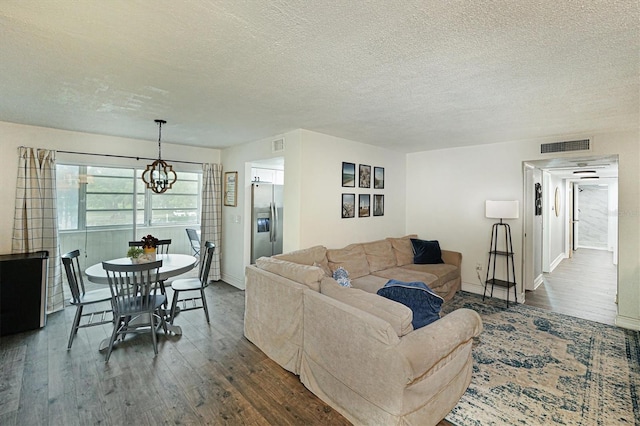 living room with a chandelier, a textured ceiling, and dark wood-type flooring