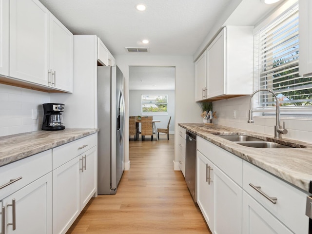 kitchen featuring sink, white cabinets, stainless steel appliances, and light wood-type flooring