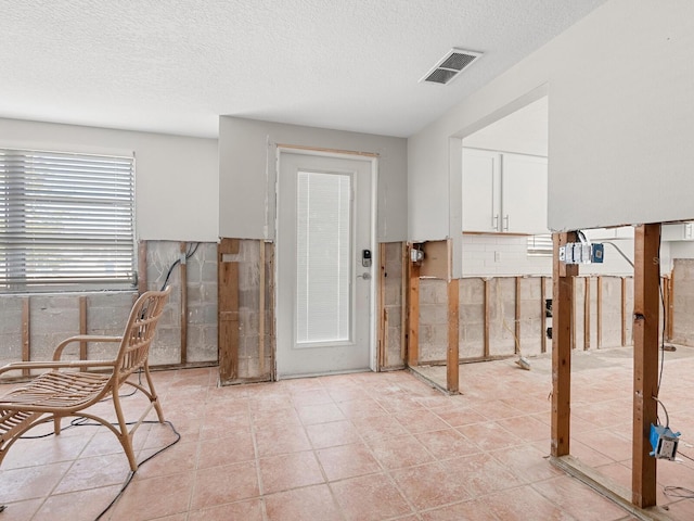 foyer featuring a textured ceiling, tile walls, and light tile patterned flooring