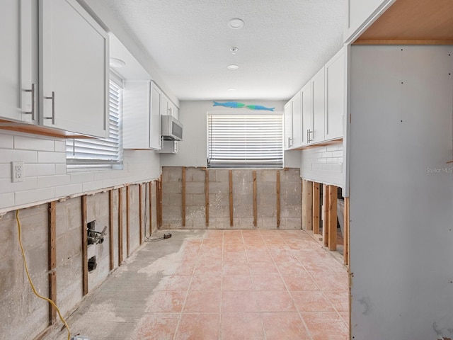 kitchen with white cabinetry, light tile patterned floors, and a textured ceiling