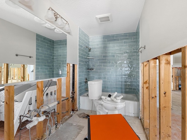 bathroom with tiled shower / bath combo, tile patterned flooring, a textured ceiling, toilet, and tile walls