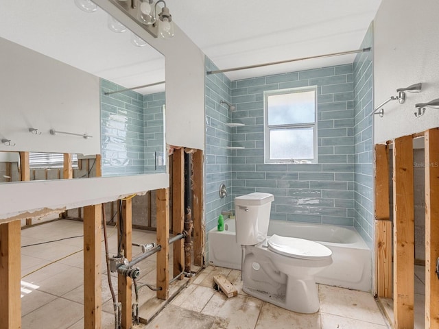 bathroom with tile patterned flooring, tiled shower / bath combo, toilet, and tile walls