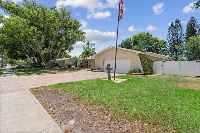 view of front of home with an attached garage, fence, decorative driveway, and a front yard