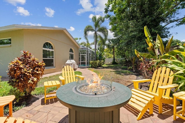 view of patio / terrace featuring glass enclosure and an outdoor fire pit