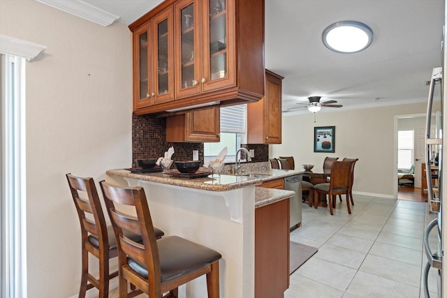 kitchen with a peninsula, brown cabinetry, a kitchen breakfast bar, and a sink