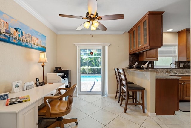 interior space with light stone counters, brown cabinets, glass insert cabinets, a sink, and a kitchen bar