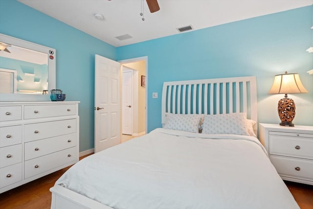 bedroom featuring a ceiling fan, visible vents, dark wood finished floors, and baseboards