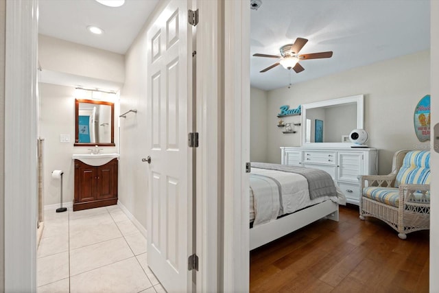 bedroom with light wood-type flooring, ceiling fan, baseboards, and a sink