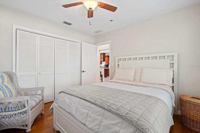 bedroom with a closet, dark wood-style flooring, visible vents, and a ceiling fan