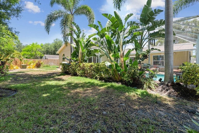 view of yard featuring a lanai, fence, and an outdoor pool