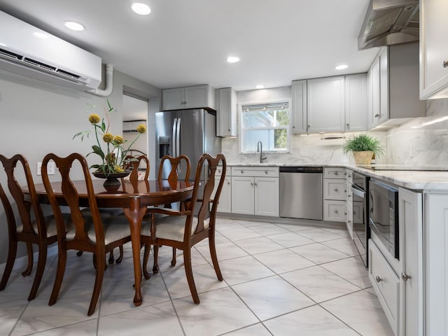 kitchen with sink, stainless steel appliances, wall chimney range hood, tasteful backsplash, and a wall mounted AC