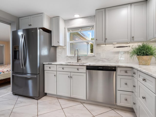 kitchen with light stone countertops, decorative backsplash, sink, and stainless steel appliances