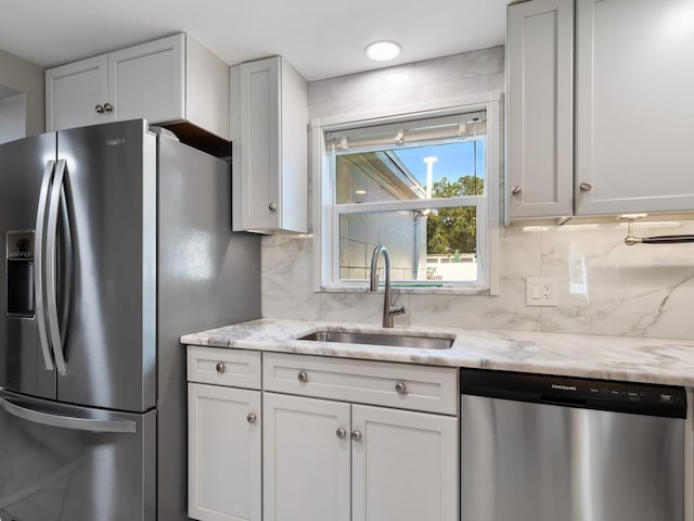 kitchen featuring tasteful backsplash, light stone countertops, sink, and stainless steel appliances