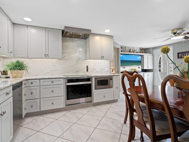 kitchen featuring black appliances, wall chimney exhaust hood, ceiling fan, decorative backsplash, and light stone counters