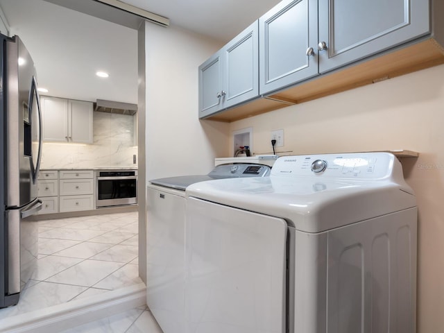 clothes washing area with washing machine and dryer and cabinets