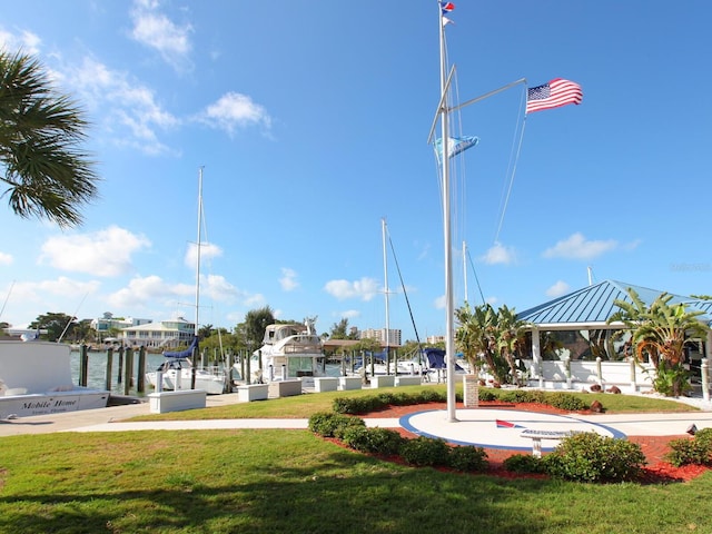 surrounding community with a lawn, a water view, and a boat dock