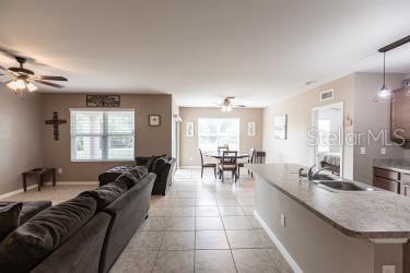 tiled living room with plenty of natural light, sink, and ceiling fan