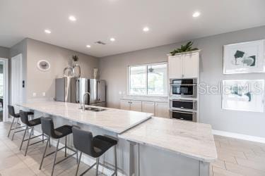 kitchen with a kitchen breakfast bar, a peninsula, white cabinetry, and appliances with stainless steel finishes