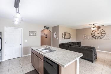 kitchen featuring light tile patterned floors, a center island with sink, ceiling fan, black dishwasher, and sink