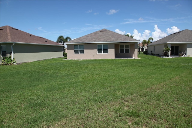 rear view of property with stucco siding and a yard