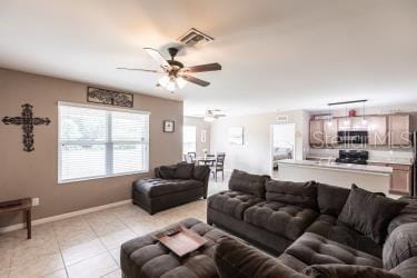 living room featuring light tile patterned floors, baseboards, visible vents, and a ceiling fan