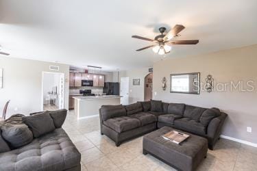 living room with light tile patterned floors, baseboards, and a ceiling fan