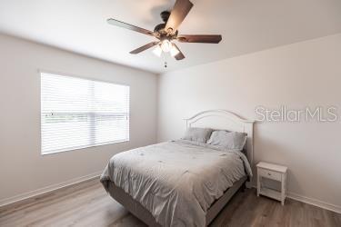 bedroom featuring baseboards, wood finished floors, and a ceiling fan