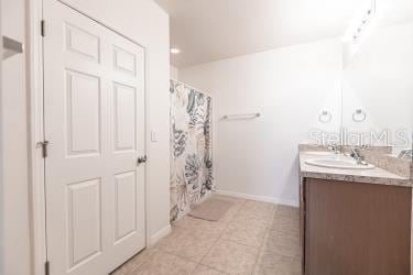 bathroom featuring baseboards, tile patterned flooring, vanity, and a shower with curtain