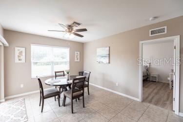 dining space with baseboards, ceiling fan, visible vents, and light tile patterned floors