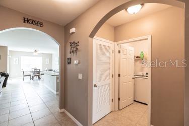 hall featuring baseboards, arched walkways, and light tile patterned floors