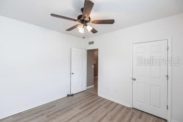 unfurnished bedroom with light wood finished floors, visible vents, and ceiling fan
