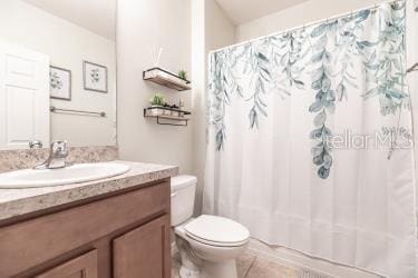 bathroom featuring a shower with shower curtain, toilet, tile patterned flooring, and vanity