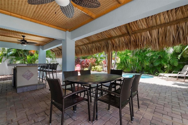 view of patio / terrace with outdoor dry bar, ceiling fan, a gazebo, outdoor dining area, and an outdoor pool