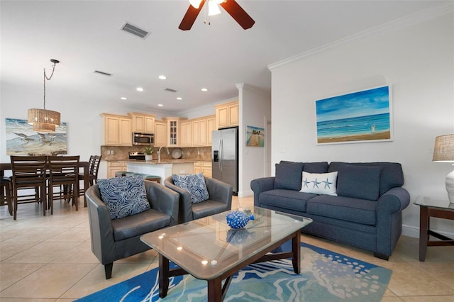 living room with ceiling fan, light tile patterned floors, ornamental molding, and sink