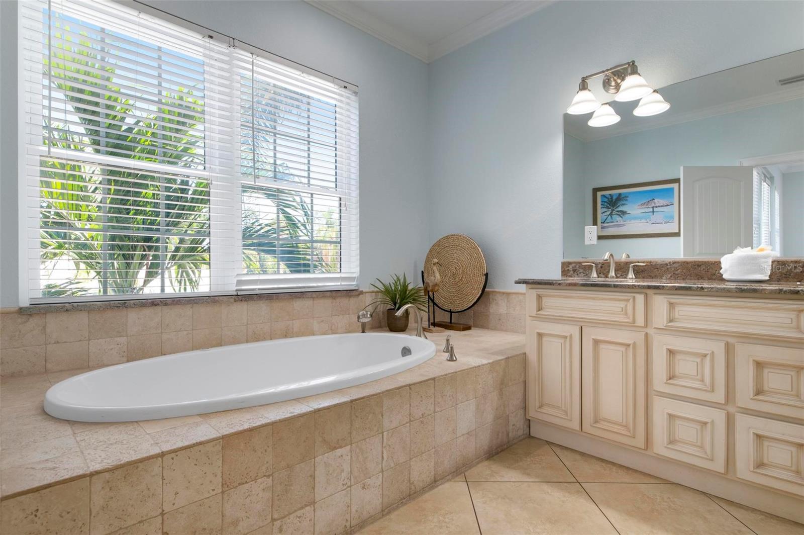 bathroom with a relaxing tiled tub, tile patterned floors, vanity, and ornamental molding