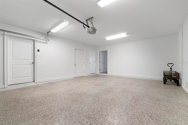 garage featuring a garage door opener and baseboards