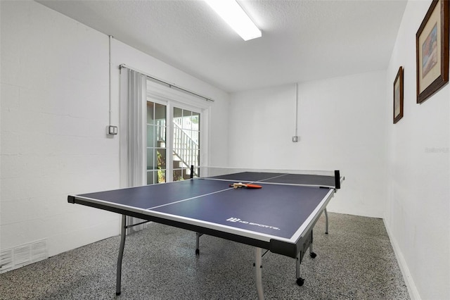 playroom with visible vents, a textured ceiling, speckled floor, and concrete block wall