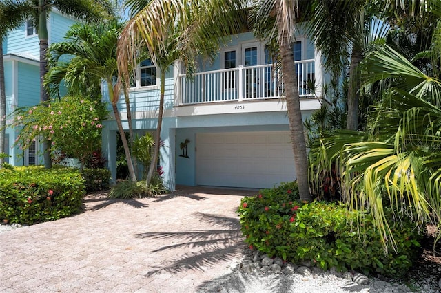 view of front of property featuring stucco siding, decorative driveway, a garage, and a balcony