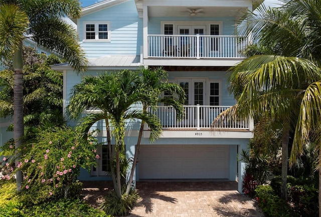 back of house featuring a ceiling fan, decorative driveway, french doors, a garage, and a balcony