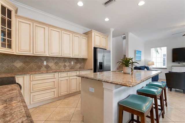 kitchen featuring open floor plan, cream cabinetry, visible vents, and stainless steel fridge