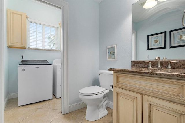 bathroom featuring washing machine and clothes dryer, tile patterned flooring, baseboards, toilet, and vanity