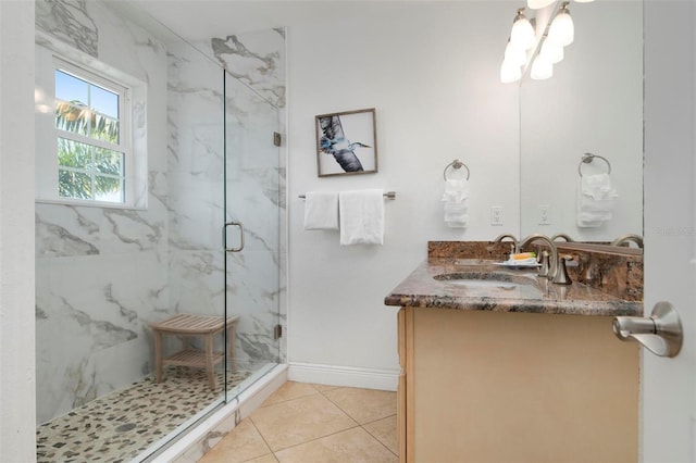 bathroom featuring vanity, tile patterned floors, baseboards, and a marble finish shower