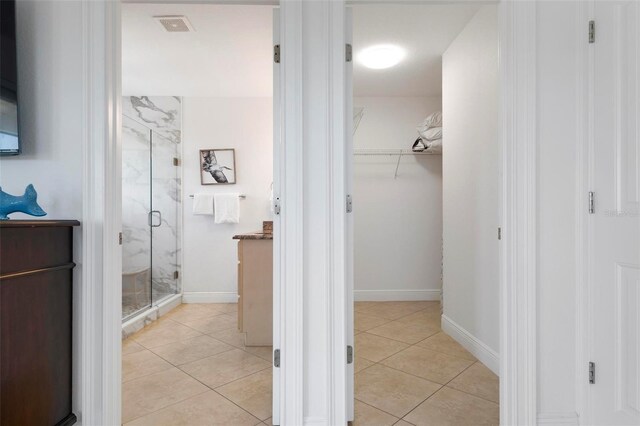 bathroom featuring vanity, tile patterned floors, a spacious closet, and a marble finish shower