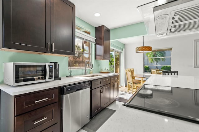 kitchen with dark brown cabinetry, dishwasher, sink, decorative light fixtures, and range