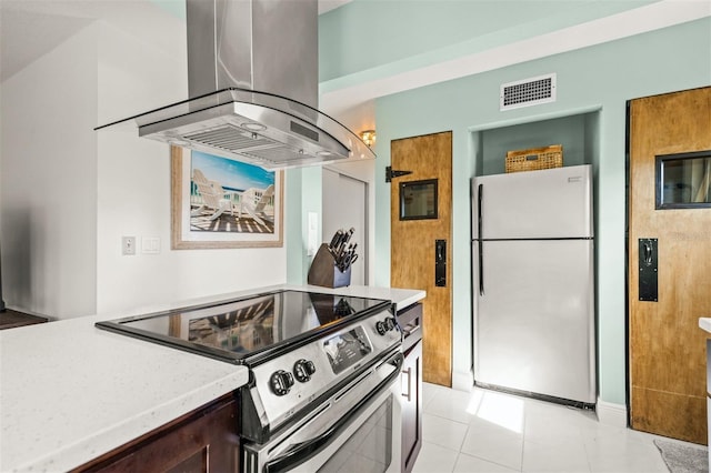 kitchen featuring stainless steel electric range, white refrigerator, light tile patterned flooring, and island exhaust hood