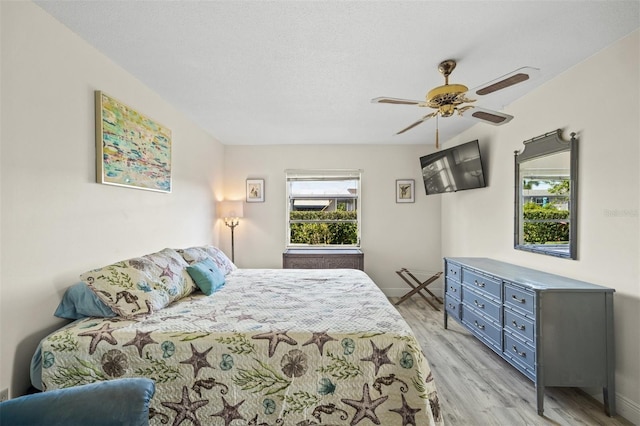 bedroom with a textured ceiling, light wood-type flooring, and ceiling fan