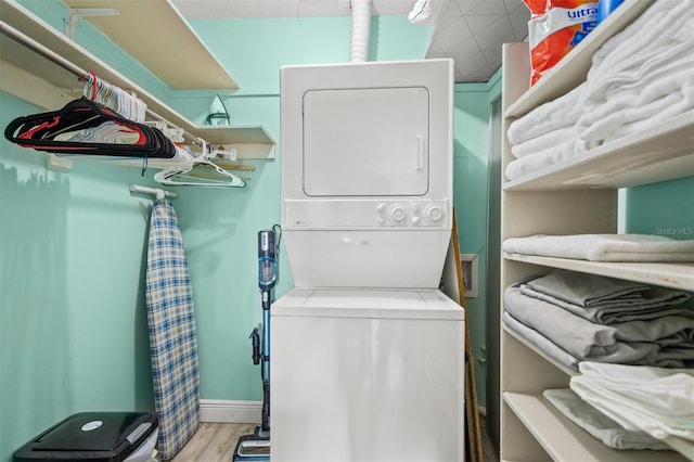 laundry area with light wood-type flooring and stacked washer and dryer